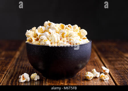 Una ciotola con popcorn su uno sfondo di legno. Foto Stock