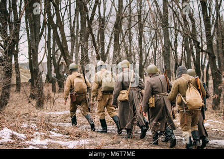 Gruppo di re-enactors vestito come Soviet russo Rosso esercito di soldati di fanteria della II Guerra Mondiale in marcia lungo la strada forestale a stagione autunnale. Foto Stock