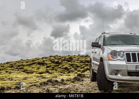 Lava vulcanica campi coperti di MOSS, con 4x4 off-road jeep in primo piano, Islanda Foto Stock