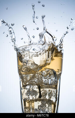 Il cubo di ghiaccio schizzi su un bicchiere di bibita Foto Stock