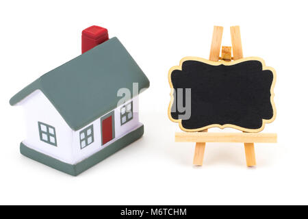 Blackboard etichetta e modello in miniatura della casa isolata su sfondo bianco, copia dello spazio. Foto Stock