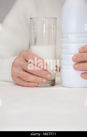 Vecchia donna nel suo 80s mantiene un bicchiere di latte Foto Stock