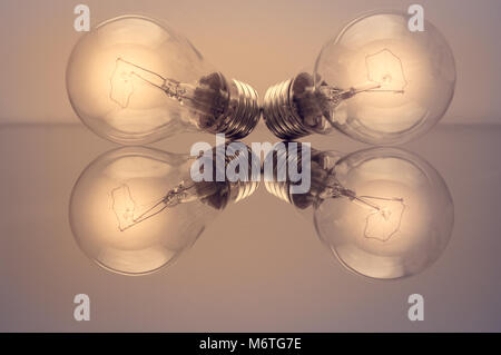 Concetto di idee brillanti per il business con due lampadine su un tavolo di vetro. Foto Stock