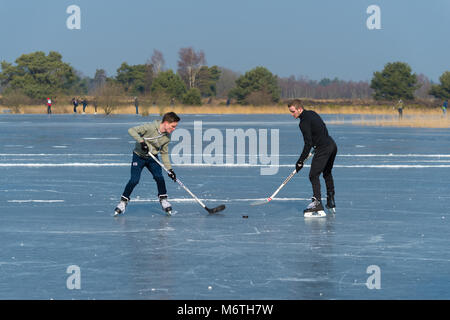 LATTROP, Paesi Bassi - 3 Marzo 2018: due ragazzi sconosciuti la riproduzione di hockey su ghiaccio su un laghetto congelato Foto Stock