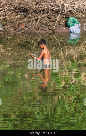 Un giovane ragazzo catturare un pesce nel fiume Irrawaddy. Mandalay, Myanmar (Birmania). Foto Stock
