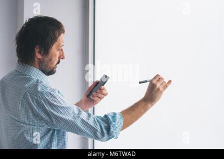 Imprenditore in office scrivere sulla lavagna con un pennarello pennarello Foto Stock