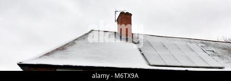 Pannelli fotovoltaici su un tetto coperto di neve Foto Stock