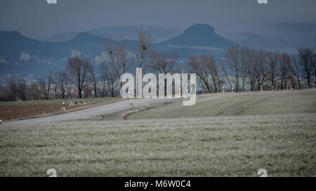 Biker/ciclista scendendo una strada, sullo sfondo delle nuvole e sulle montagne della Svizzera Sassone può essere visto (Dresda/Bannewitz, Germania) Foto Stock