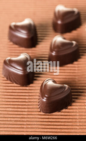 Cioccolatini a forma di cuore su uno sfondo marrone Foto Stock