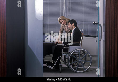 1995 caucasico storico Business donna parlando di disabile business uomo seduto nella sedia a rotelle IN UFFICIO Foto Stock