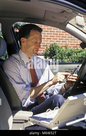 1995 caucasico storico vendite business man con telefono cellulare (©MOTOROLA CORP 1995) IN AUTOMOBILE MOBILE OFFICE Foto Stock