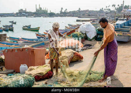 Due pescatori che riparano le reti a Vizhinjam Fishing Village, Kerala, India Foto Stock