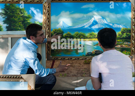 Due uomini di discutere la qualità di un paesaggio dipinto al vernissage a Yerevan, Armenia. Foto Stock