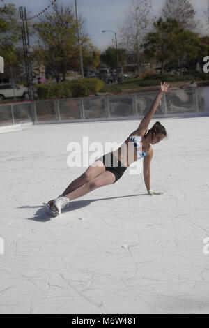 Ragazza adolescente pattinaggio sul ghiaccio all'aperto in pantaloncini corti e un bikini top nel sud Califiornia in 85 grado inverno meteo Foto Stock
