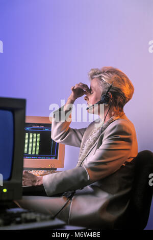 1996 caucasico storico vendite telefoniche donna seduta alla scrivania del computer in ufficio indossando con fili cuffia telefonica Foto Stock