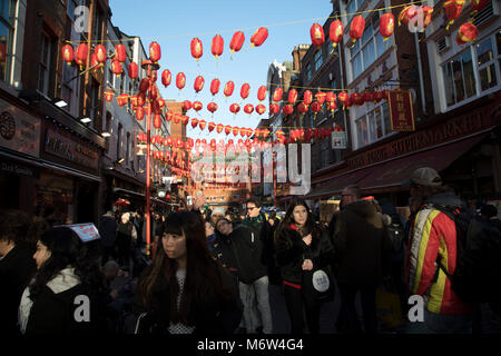 Rosso e giallo lanterne sono infilate tra gli edifici creando un baldacchino di colore per il nuovo anno cinese su Gerrard Street, Soho, noto anche come Chinatown a Londra, Inghilterra, Regno Unito. Comunità cinese di raccogliere su questa famosa strada del centro di Londra che è il focus delle celebrazioni. Foto Stock