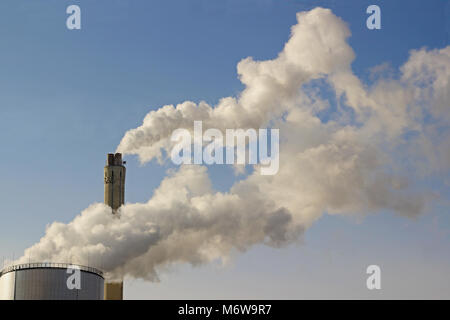 Nuvole di vapore da camini industriali di fronte blu cielo Foto Stock