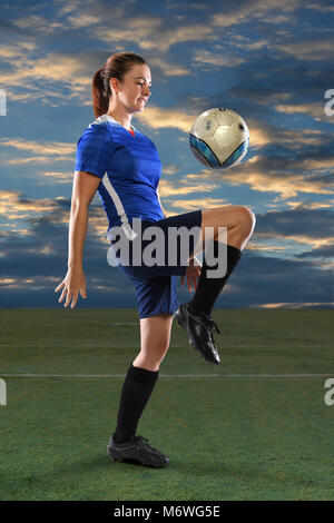 Calcio femminile player la pallina che rimbalza sul ginocchio al crepuscolo Foto Stock