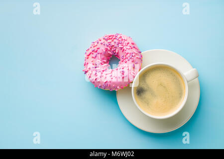 Ciambella di rosa e la tazza di caffè su sfondo blu. Foto Stock