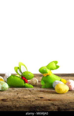 Pasqua conigli fatti a mano su un tavolo di legno con uova isolate su bianco. Foto Stock