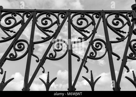 Vecchia recinzione arrugginita contro un nuvoloso cielo scuro Foto Stock