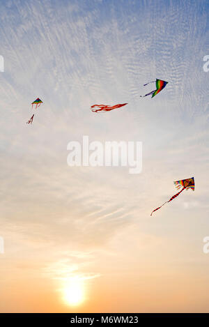 Vista verticale di aquiloni volare nel cielo al tramonto. Foto Stock