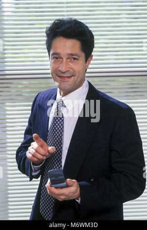 1998 RITRATTO STORICO DI UOMO D'AFFARI CAUCASICO IN OFFICE HOLDING CELLULARE Foto Stock
