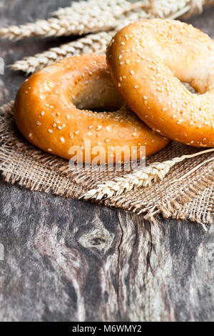 Il SESAMO bagel e spighe di grano su un letto di sacco igienico Foto Stock