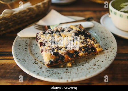 Close-up pezzo di torta dolce con dessert forcella sul piattino sullo sfondo delle piastre sfocate con il cibo sulla tavola di legno Foto Stock