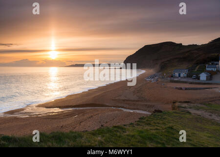 Seatown, Dorset, Regno Unito. Il 6 marzo 2018. Regno Unito Meteo. Un fascio di luce del sole splende alto sul livello alto nuvole che sono parzialmente oscurando il tramonto a Seatown su Jurassic Coast di Dorset. Credito Foto: Graham Hunt/Alamy Live News Foto Stock