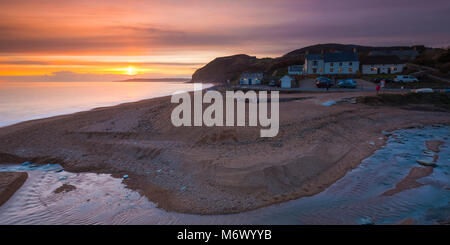 Seatown, Dorset, Regno Unito. Il 6 marzo 2018. Regno Unito Meteo. Livello alto nuvole oscura parzialmente il tramonto a Seatown su Jurassic Coast di Dorset. Nella foto è lo storico pub la Anchor Inn. Credito Foto: Graham Hunt/Alamy Live News Foto Stock