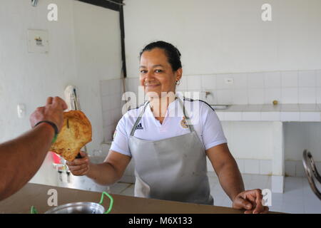 27 gennaio 2018, la Colombia, l'Agua Bonita: un ex combattente della guerriglia dell'organizzazione di guerriglia FARC serve 'Cancharinas', profondo fritto pasta sfoglia, in corrispondenza di una cucina locale. Per decenni la sinistra organizzazione di guerriglia FARC hanno combattuto contro i militari e forze di polizia in Colombia. Ora, i membri di deporre le armi e a prendere una possibilità al ritorno alla vita civile nel piccolo paese del Caquetá dipartimento. Foto: Sinikka Tarvainen/dpa Foto Stock