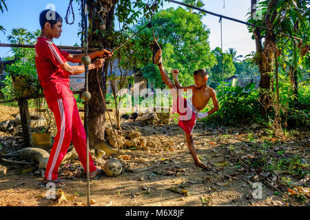 A sette anni vecchio ragazzo di formazione è la sua abilità di kickboxing, sempre teso dal suo trainer Foto Stock