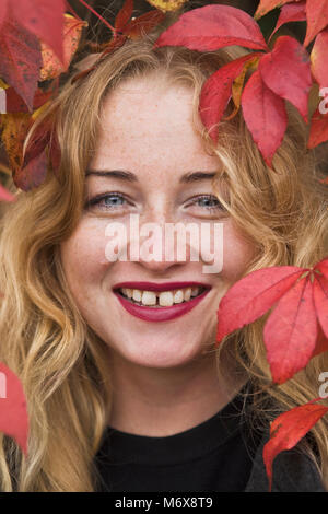 Il Sorridente donna bionda in piedi nel parco Foto Stock