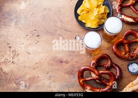 La birra, salati salatini, potato chips su sfondo di legno. Vista dall'alto. Spazio di copia Foto Stock