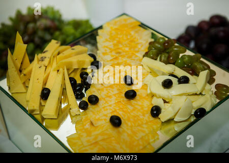 Formaggio altopiano assortiti con olive e uva servita su specchio quadrato in background servizio catering Foto Stock