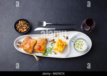 Gambe di Anatra confit, patate gratinate e salsa di funghi Foto Stock