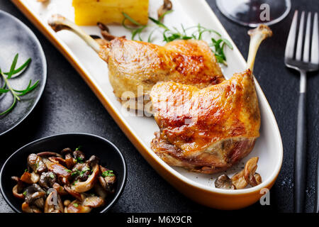 Gambe di Anatra confit, patate gratinate, sugo di funghi. Foto Stock