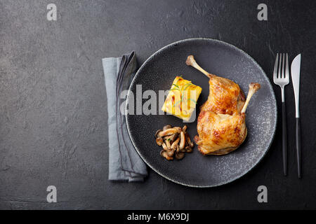 Gambe di Anatra confit, patate gratinate e salsa di funghi Foto Stock