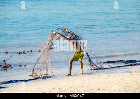 Zanzibar, Tanzania - Novembre 28, 2013: pescatore versarsi la sua rete e lo scarico di rifiuti e di sabbia la sera dopo il lavoro. Foto Stock