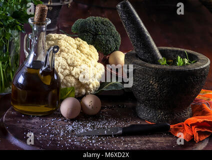 Fresche verdure crude su una tavola di legno con un mortaio e pestello. Primo piano. Studio fotografico. Foto Stock