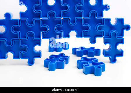 Pezzi da un blu puzzle disposti a formare una pagina su sfondo bianco. Rompere le barriere insieme per l'autismo. Foto Stock