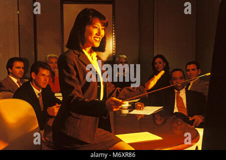 2000 Presentazione storica da donna asiatica per gruppo di multi etnico business persone che indossano tute in OFFICE SALA RIUNIONI Foto Stock