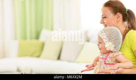 Felice madre e bambino seduti insieme sul divano nel salone luminoso Foto Stock