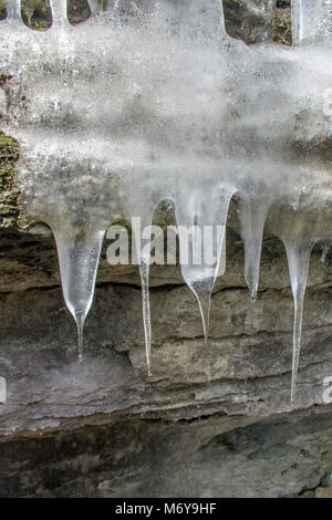 Primo piano di ghiaccioli appesi da una grotta ingresso Foto Stock