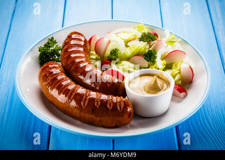 Salsicce alla griglia e verdura sul tavolo di legno Foto Stock