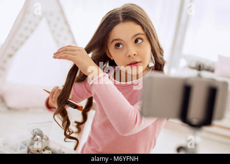 Ragazza dolce spazzolare i capelli e lo cattura Foto Stock