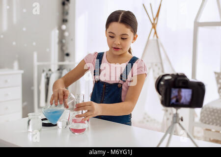 Ragazza piacevole che mostra come mescolare i prodotti chimici correttamente Foto Stock