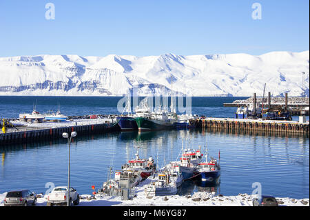 Barche da pesca, montagne innevate, cieli blu. Husavik Harbour, Islanda su un freddo inverno mattina. Foto Stock