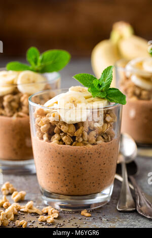 Layered cioccolato budino di chia parfait con banana, muesli e yogurt, dessert Foto Stock